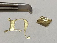 Dorure à la feuille d’or : début de la lettrine « N » , feuille d’or et brunissoir.